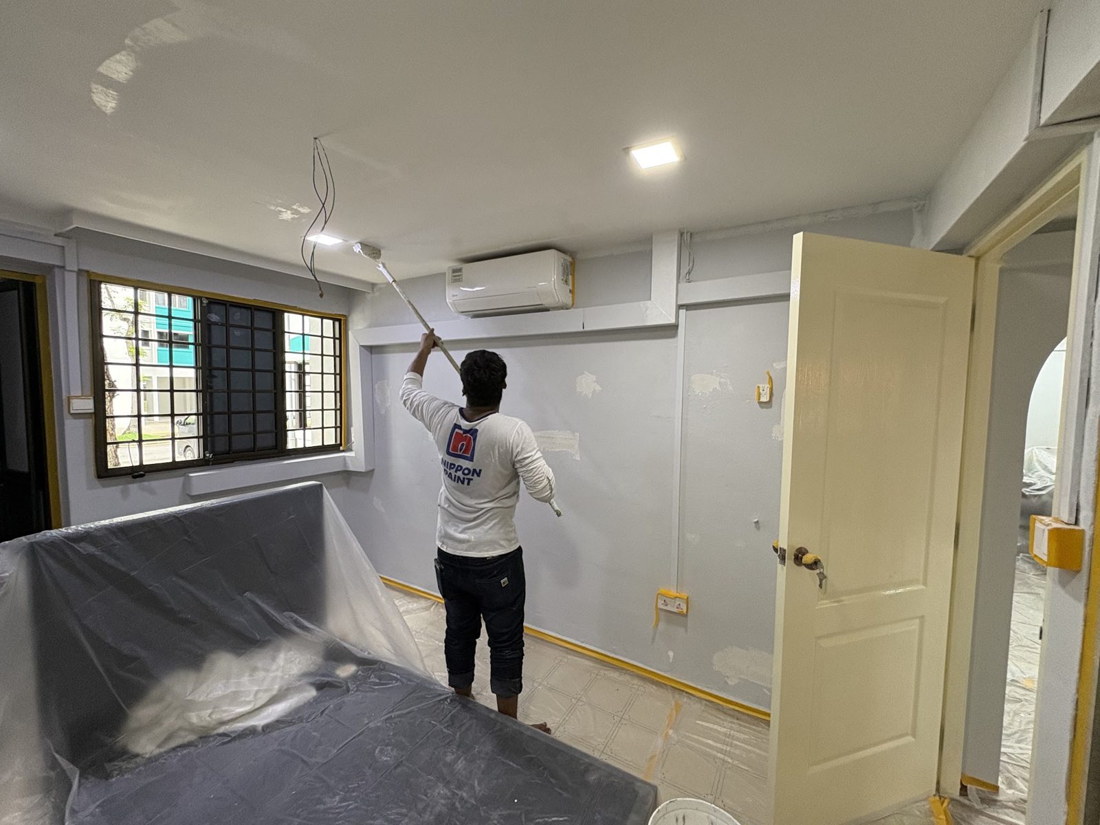 LHF painting a bedroom with the furniture sheeted, floor covered and sockets taped off